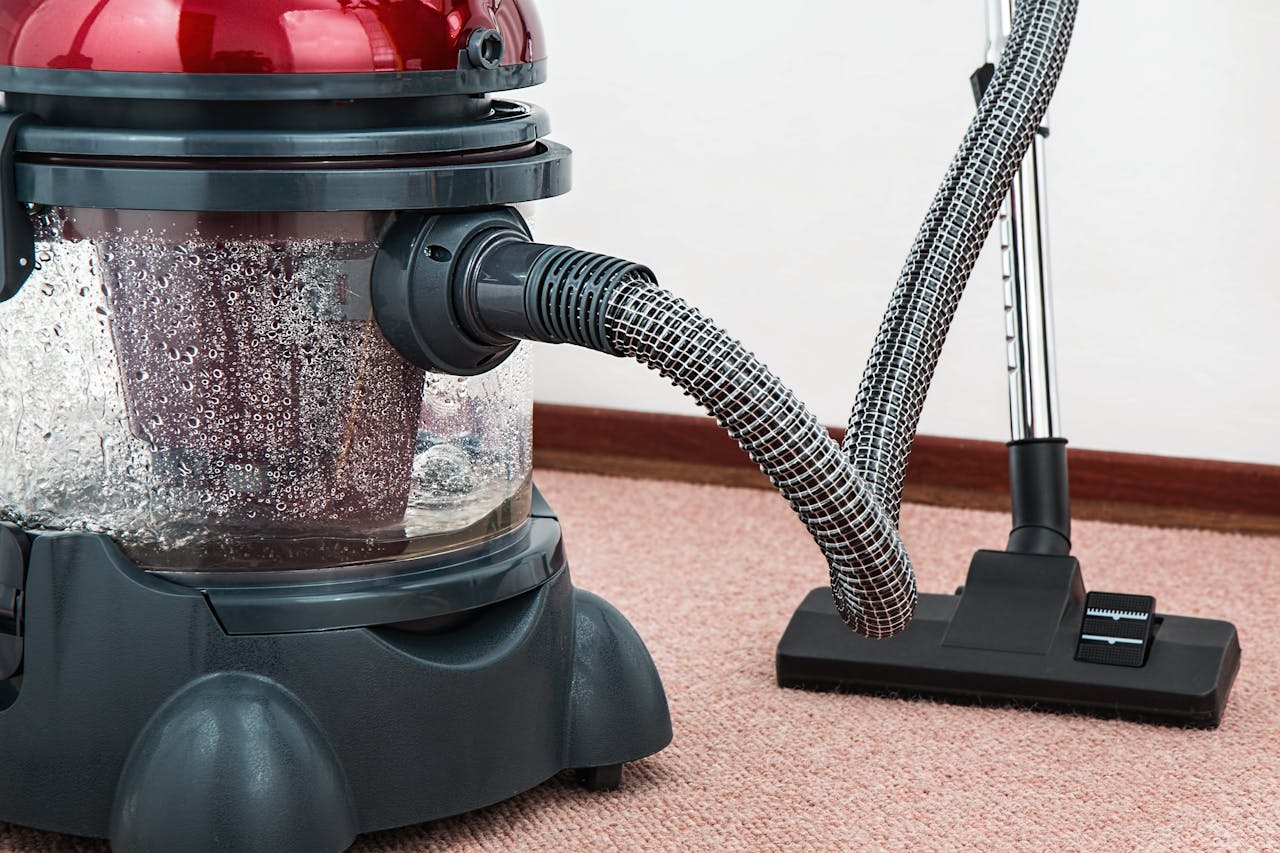 Close-up of a modern vacuum cleaner with water filtration on carpet floor indoors.