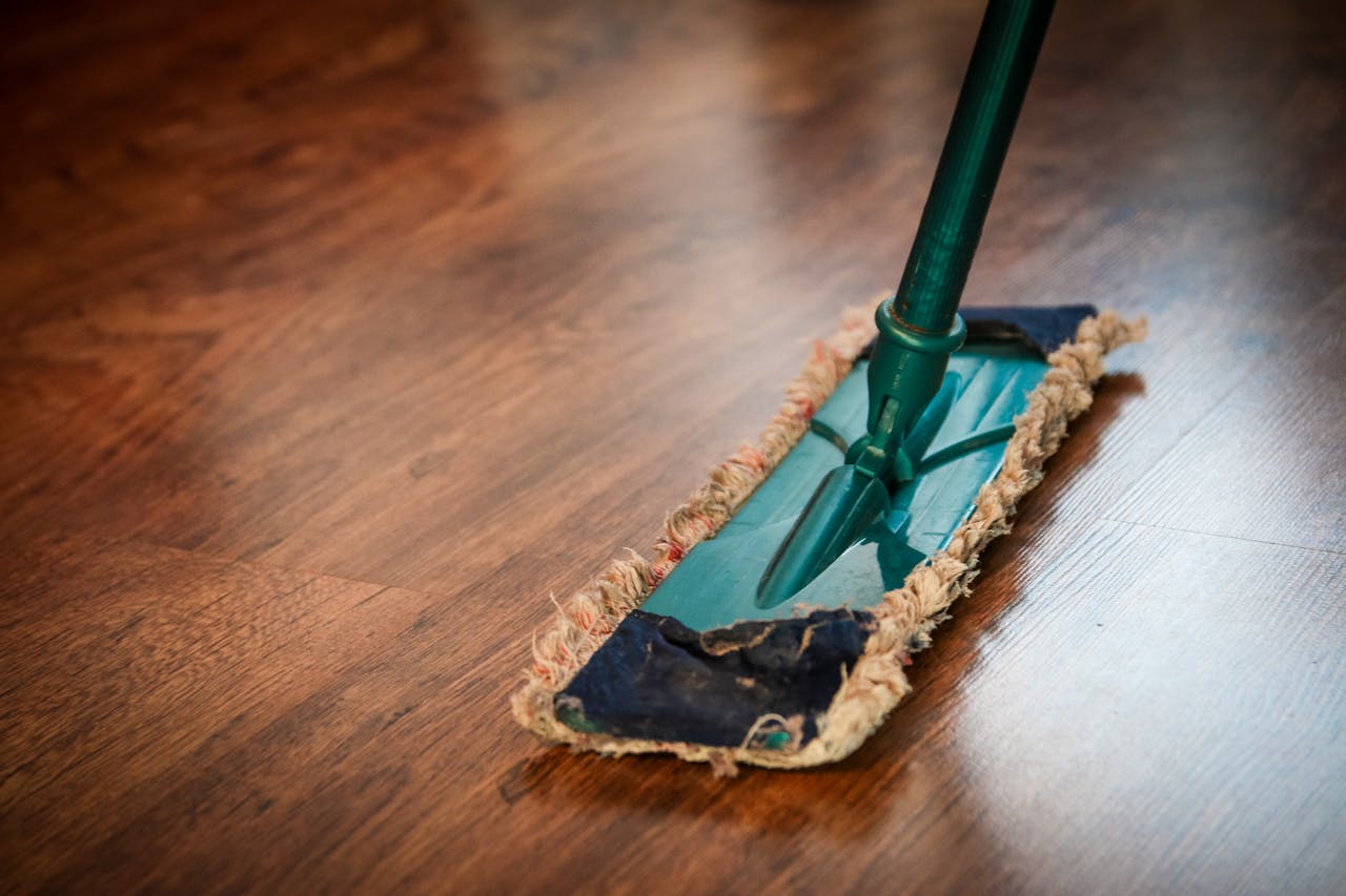 services-04 A detailed view of a mop cleaning a wooden floor, showing texture and pattern.